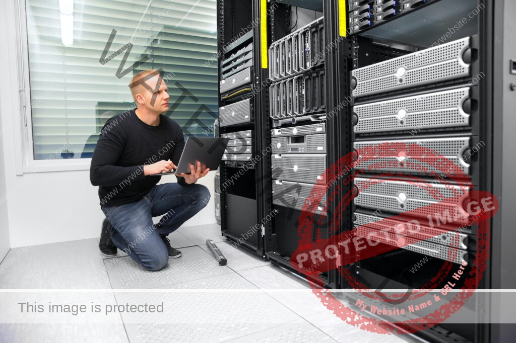 Consultant Using Laptop While Monitoring Servers In Datacenter