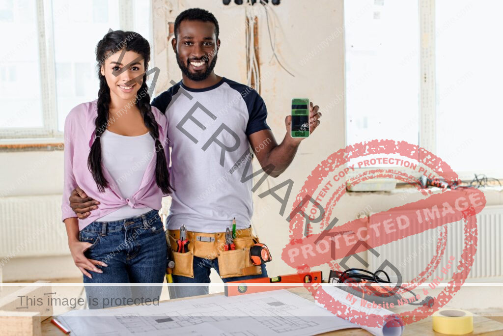 smiling couple holding smartphone with booking app on screen during renovation